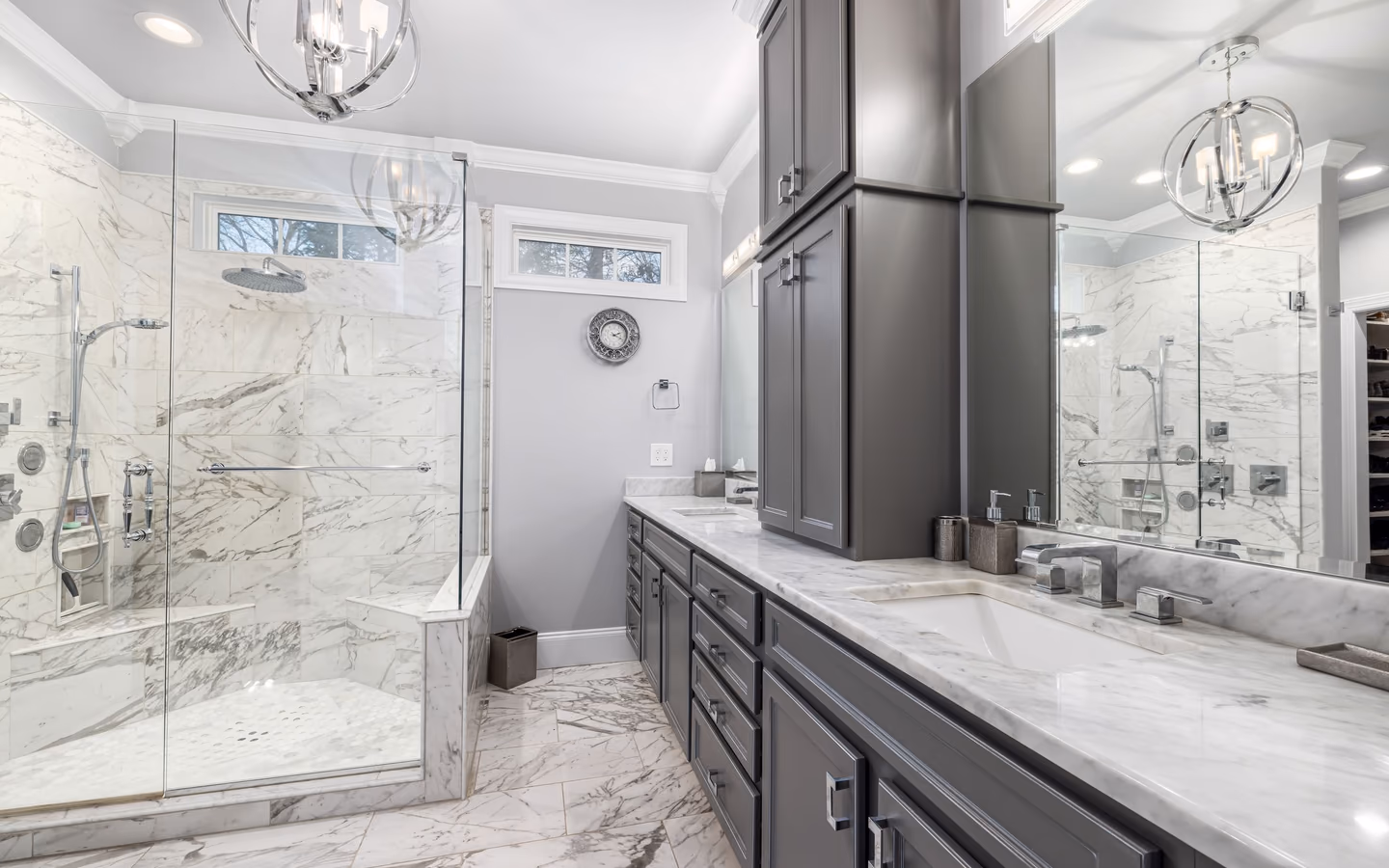 Elegant transitional bathroom with charcoal cabinetry, marble surfaces, and a glass shower