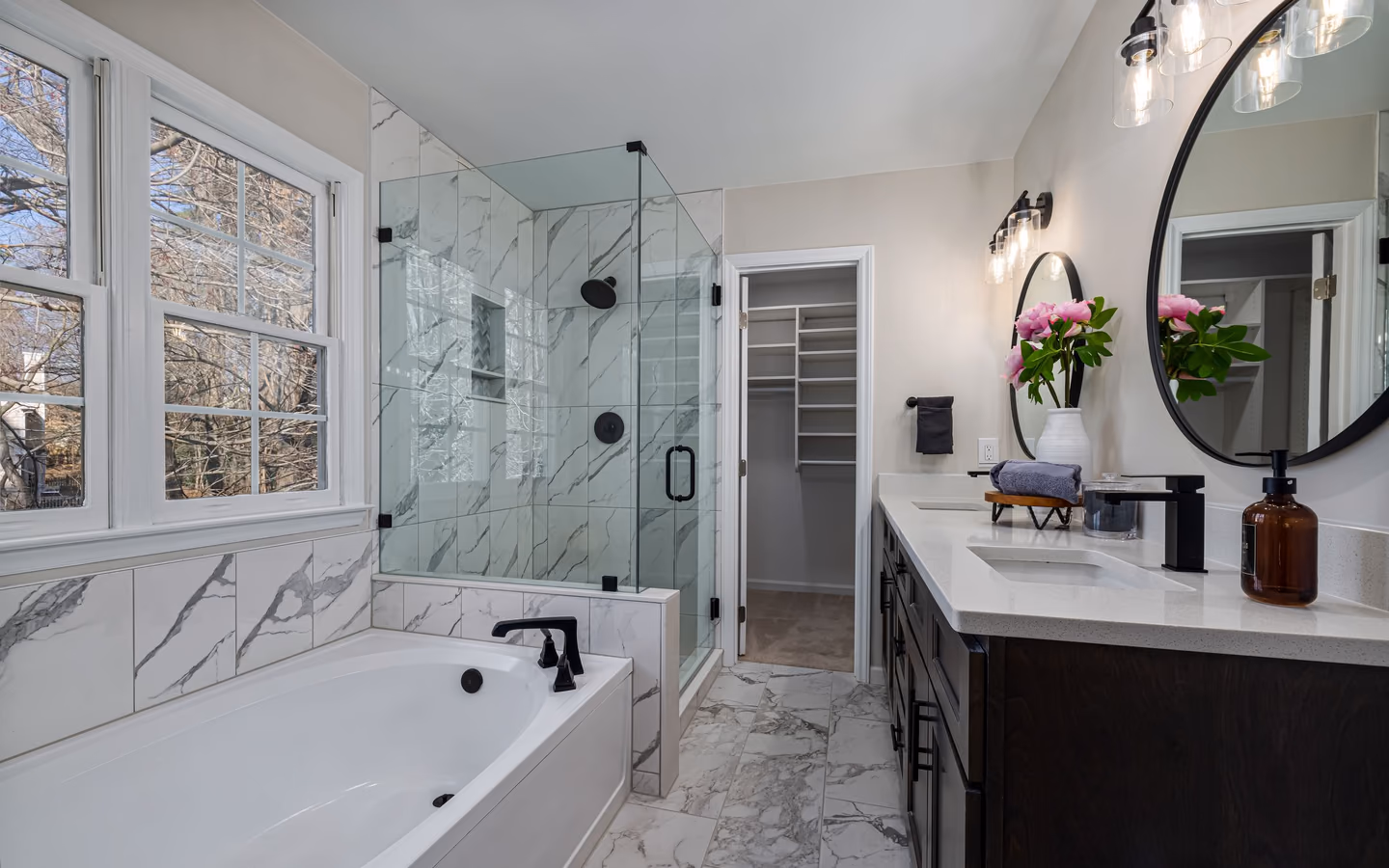 Luxurious bathroom with marble tile, a glass shower, indoor plants, and elegant lighting