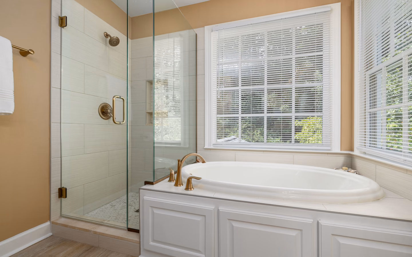 Bright spa-like bathroom with a bathtub, glass shower, and soft neutral finishes