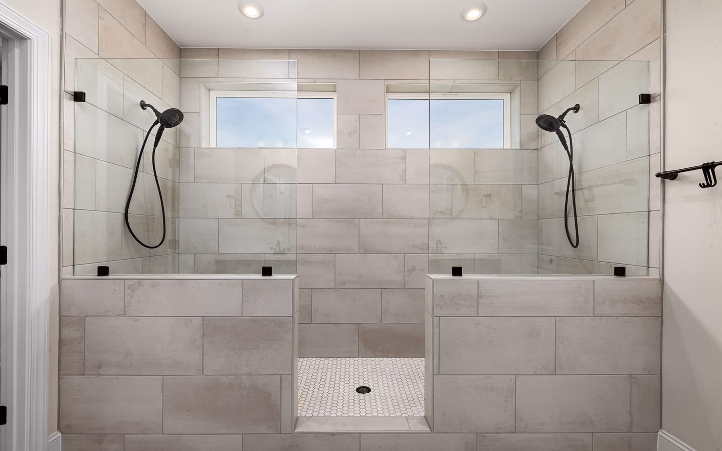 Wide open shower with dual fixtures, built-in seating, and an unobstructed tiled entry