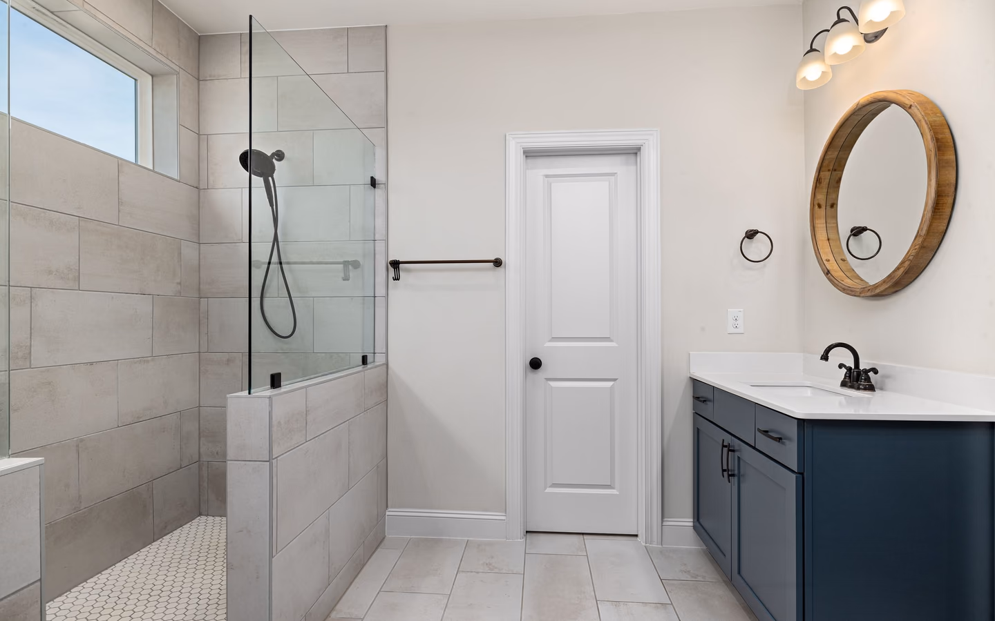 Fresh transitional bathroom with a deep blue vanity, round mirror, and open walk-in shower