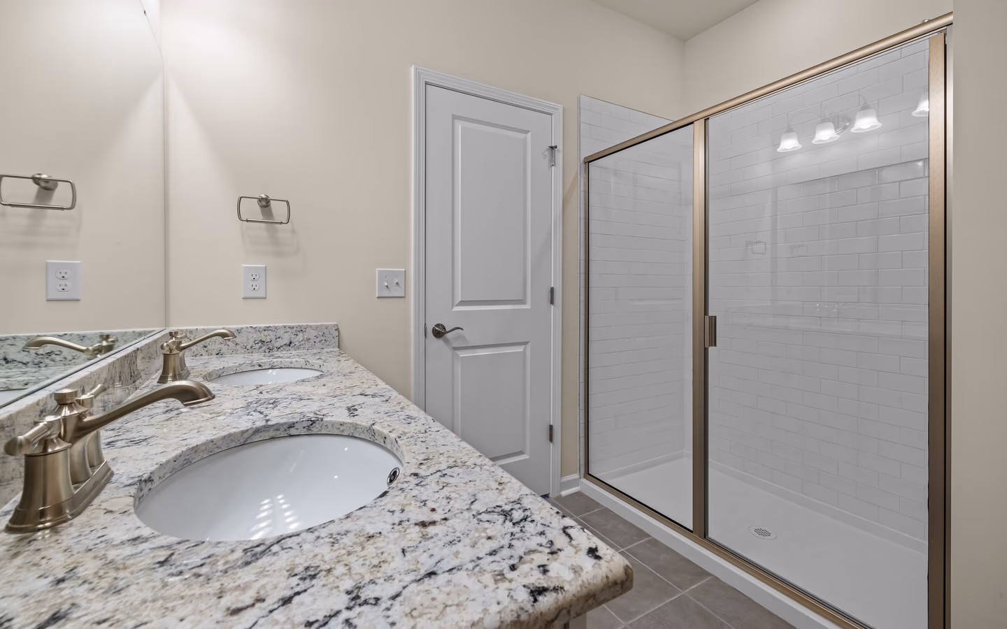 Elegant bathroom with granite counters, a spacious glass shower, and bright wall lighting