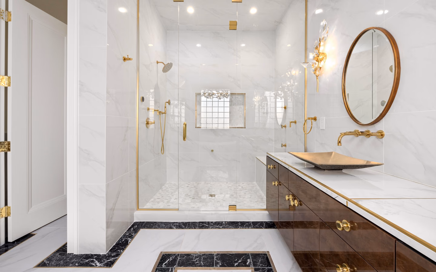 Polished transitional bathroom with white marble, a wood vanity, and warm metal fixtures