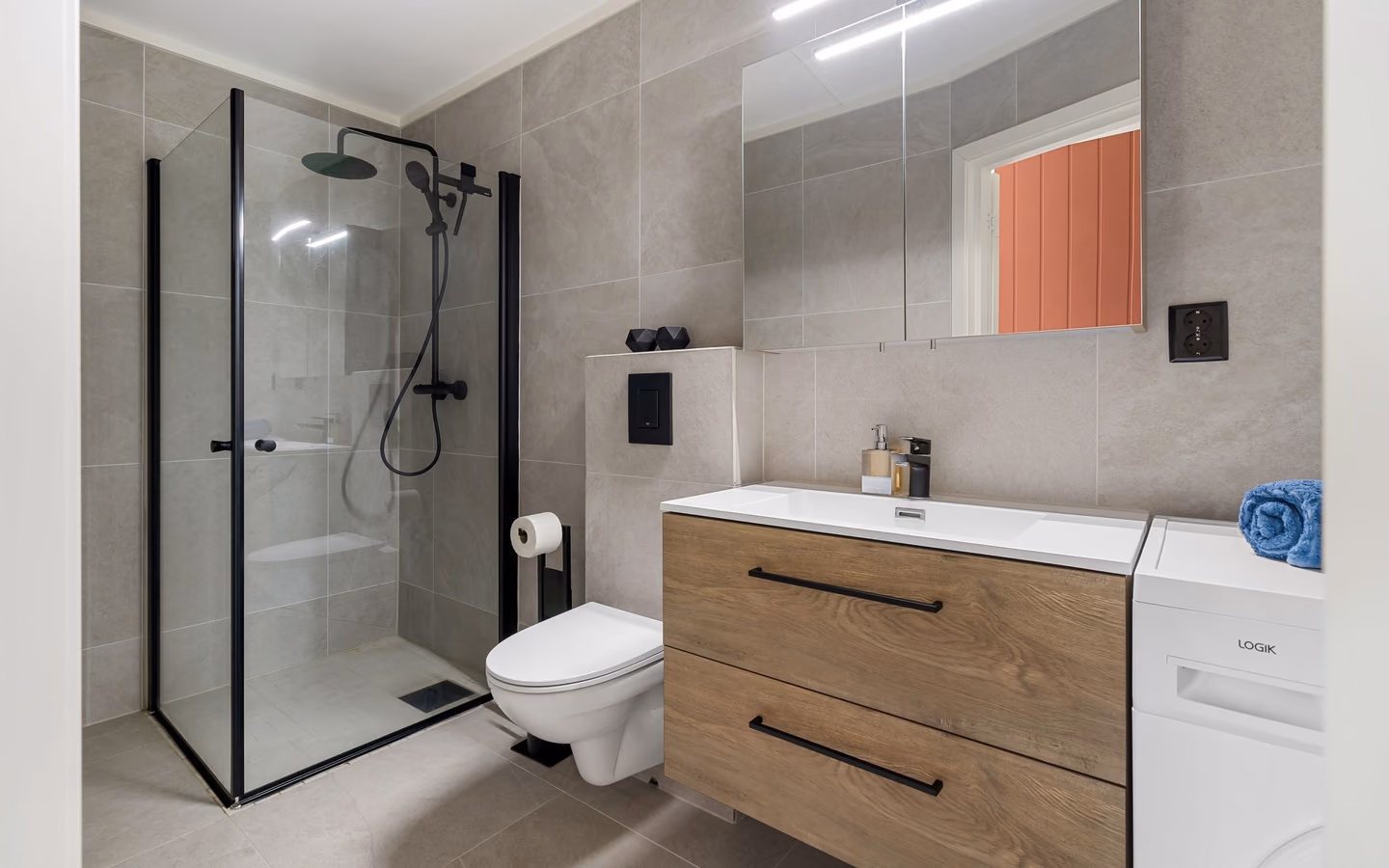 Contemporary bathroom with a light wood vanity, black fixtures, and a glass shower enclosure