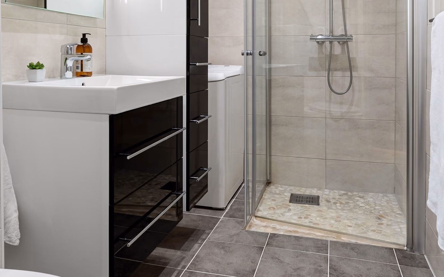 Sleek modern bathroom with a compact floating vanity, frameless glass shower, and crisp neutral tile