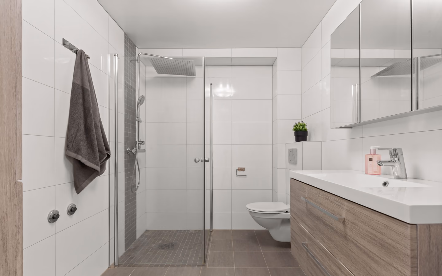 Modern bathroom with a light wood vanity, frameless shower, and integrated open storage
