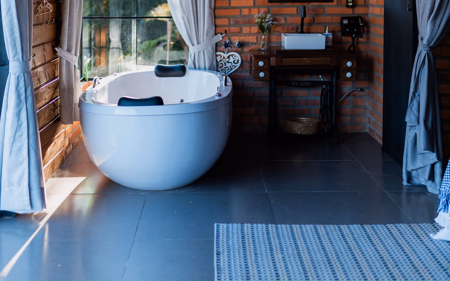 Warm spa bathroom with a freestanding tub, brick accents, and soft natural light