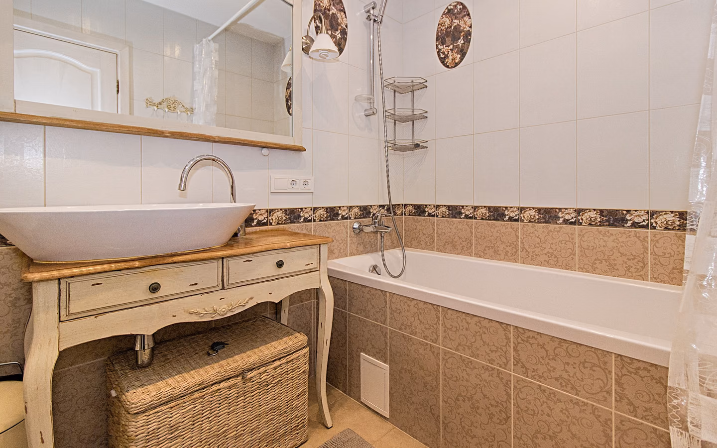 Warm traditional bathroom with a vanity, tub, wicker storage, and patterned tile