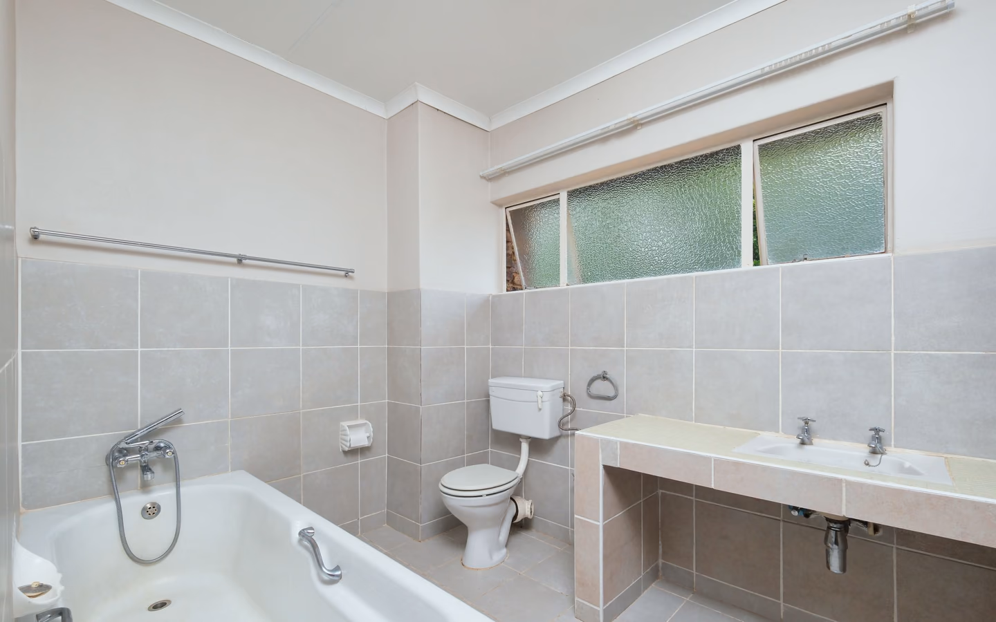 Spacious modern bathroom with clean tiled surfaces and generous natural light