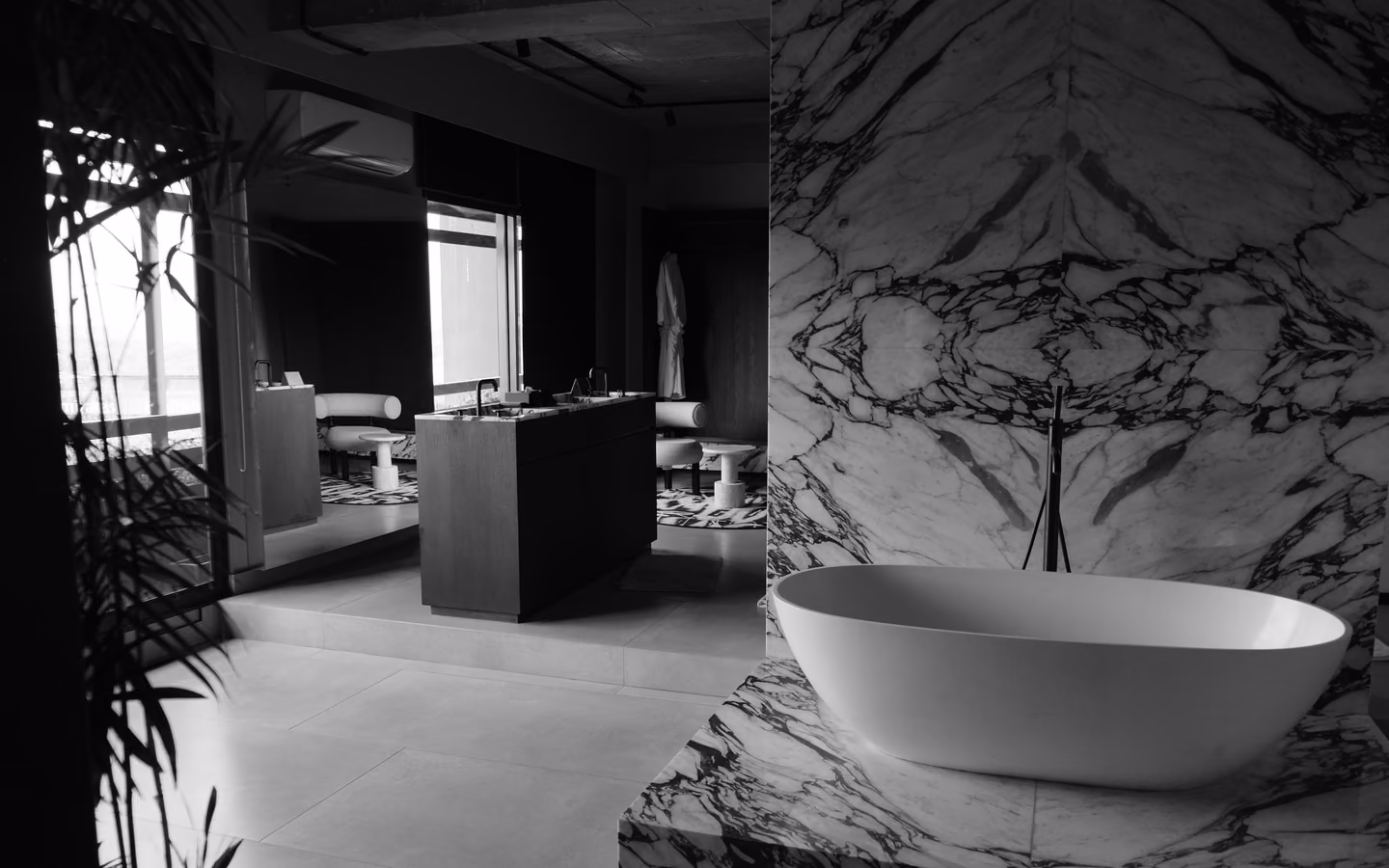 Monochrome luxury bathroom with dark marble, a white tub, and high-contrast finishes