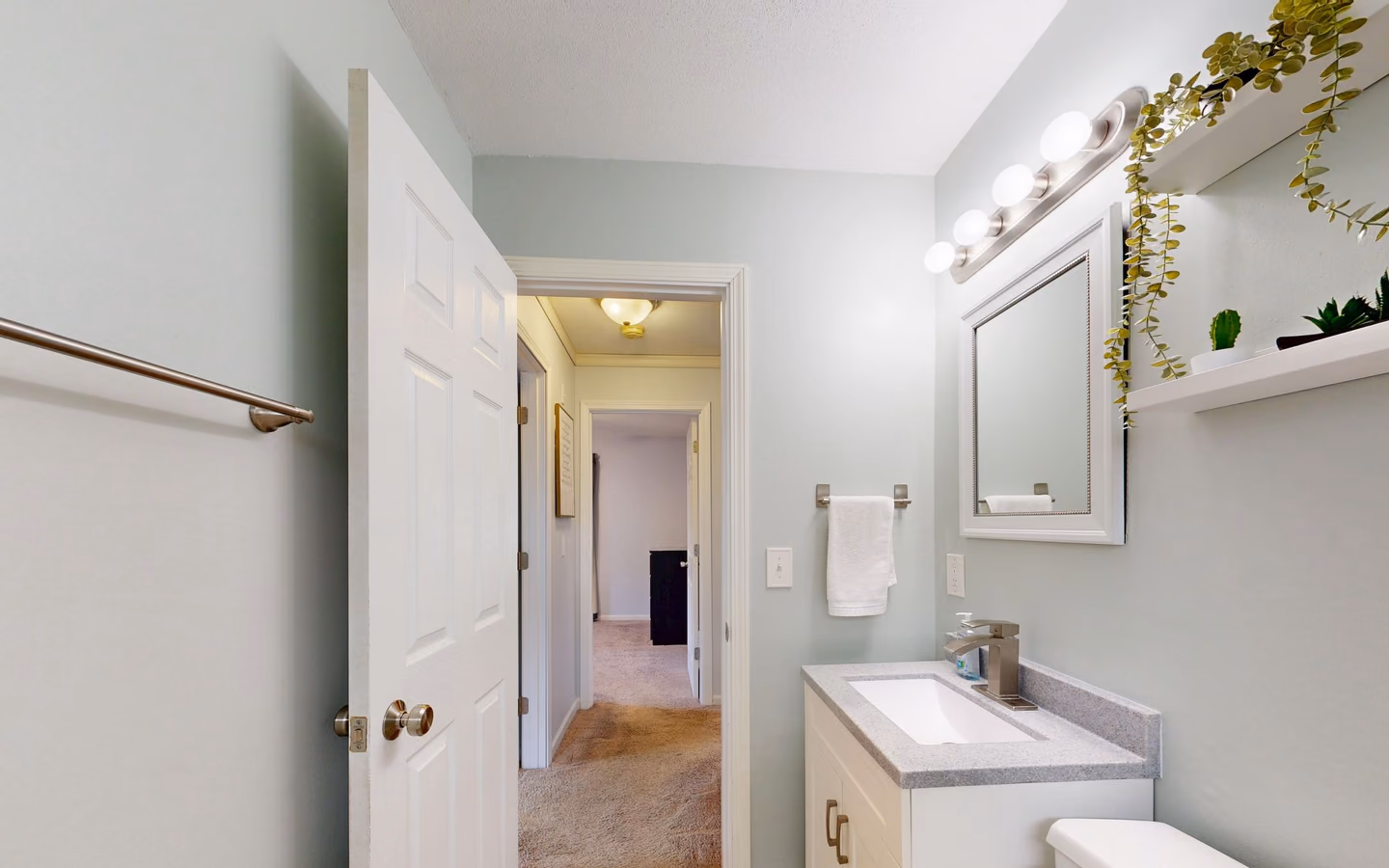 Fresh minimalist bathroom with a warm wood vanity, plants, and clean neutral finishes