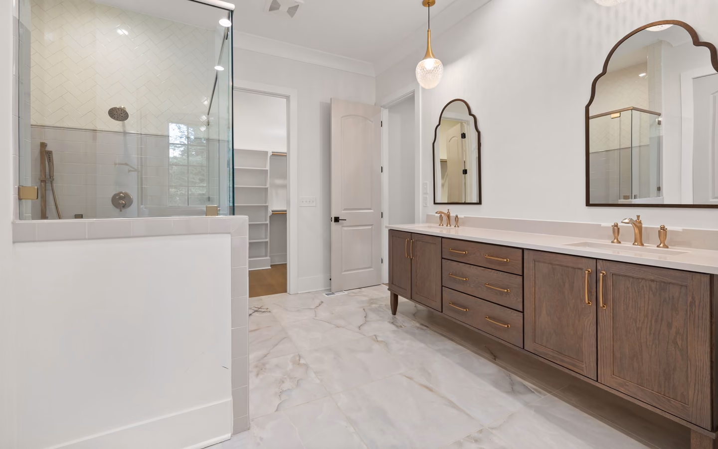 Updated transitional bathroom with a tailored double vanity, framed mirrors, and a glass shower