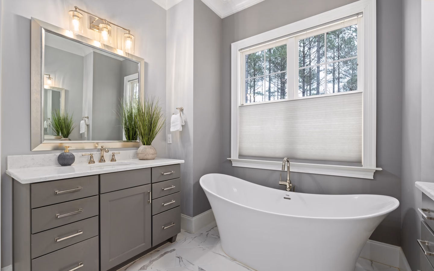 Gray vanity and freestanding tub in a bright renovated bathroom