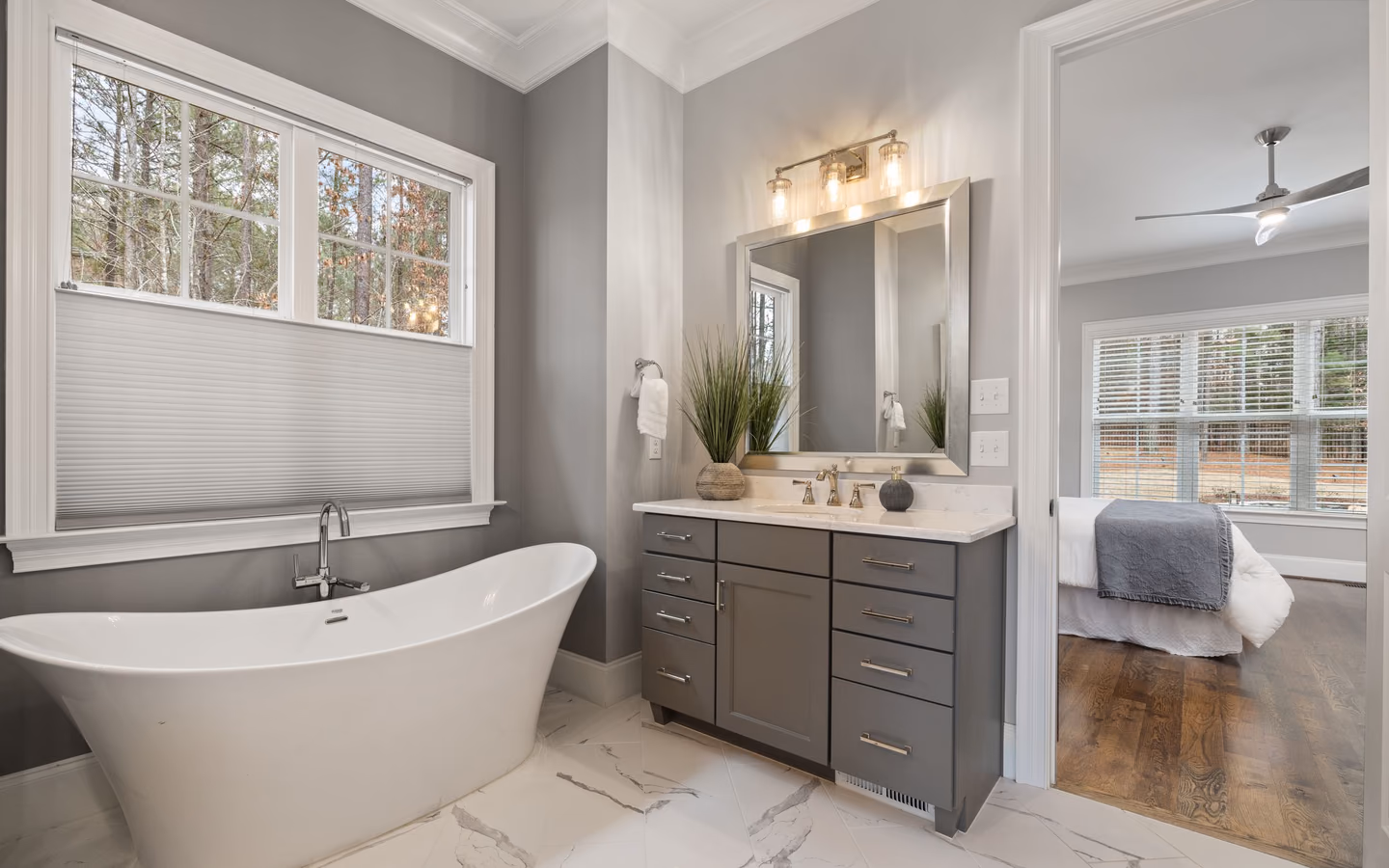 Bright modern bathroom with a freestanding tub, long gray vanity, and large mirror