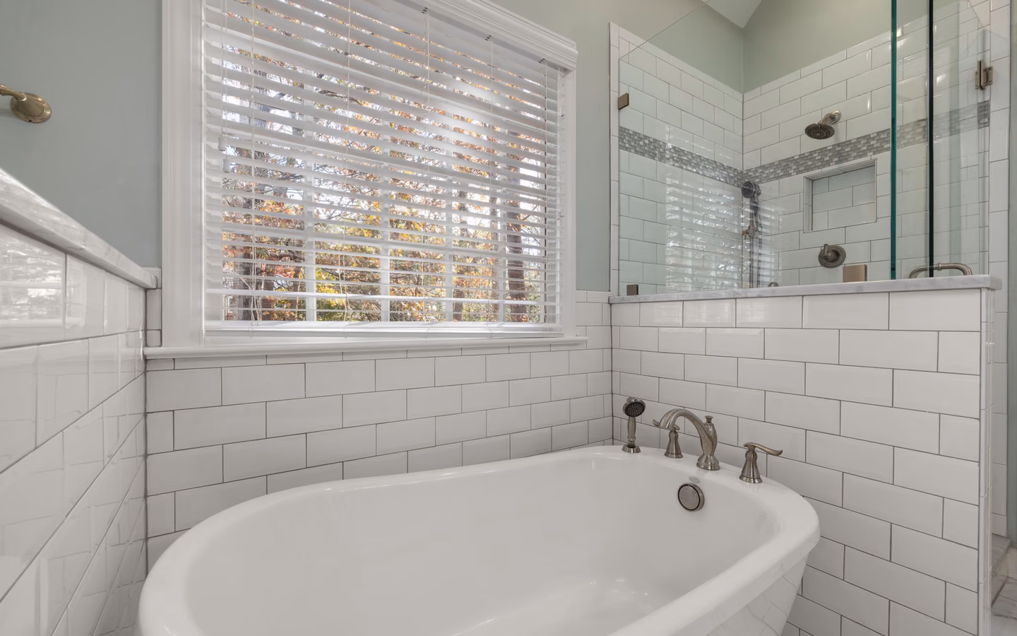 Spacious spa bathroom with a freestanding tub, glass shower, and crisp white subway tile