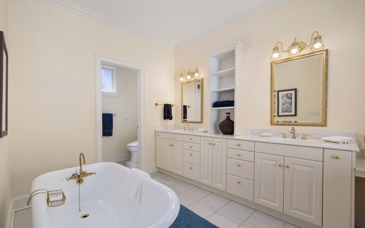 Updated traditional bathroom with a clawfoot tub, double vanity, and warm lighting
