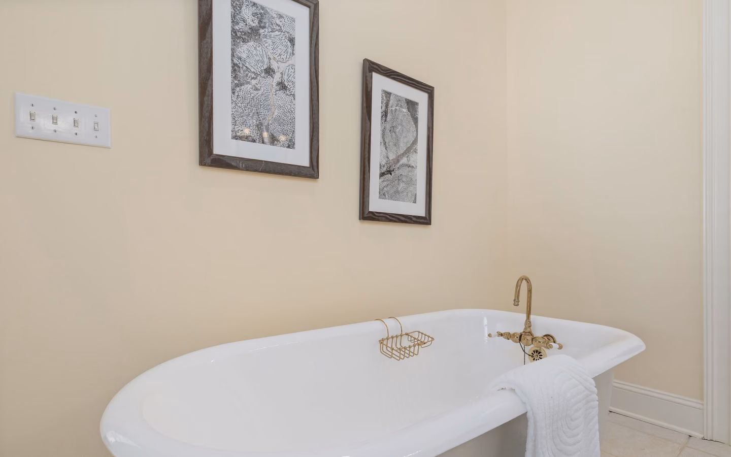 Classic bathroom with a freestanding tub, warm metal fixtures, framed art, and tailored details