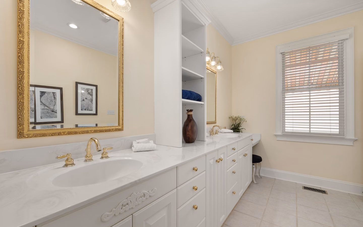 Spacious primary bathroom with a long double vanity, freestanding tub, and warm metal accents