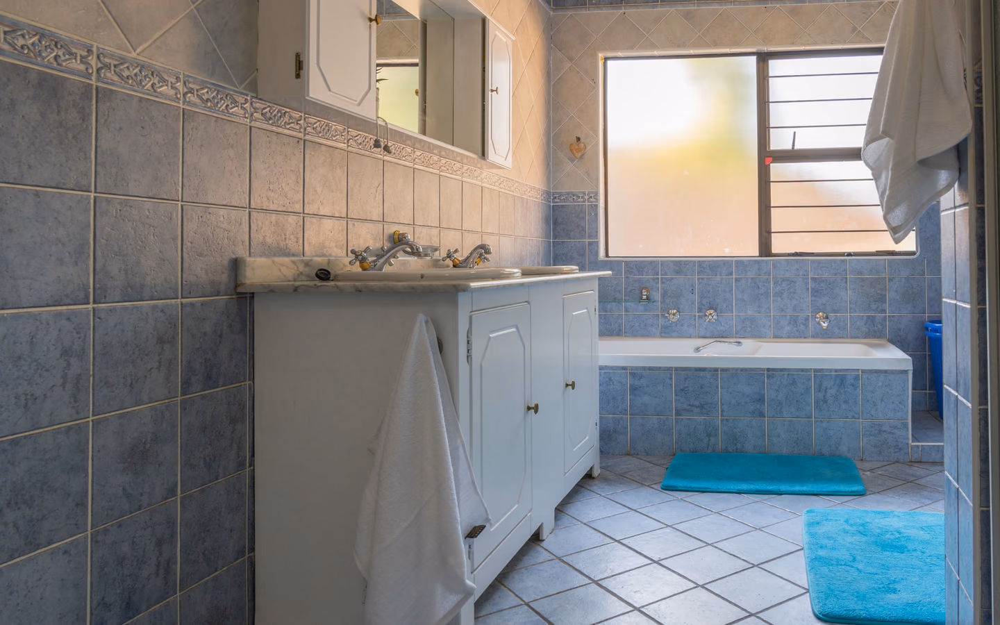 Contemporary bathroom with structured blue tile, white fixtures, and natural light