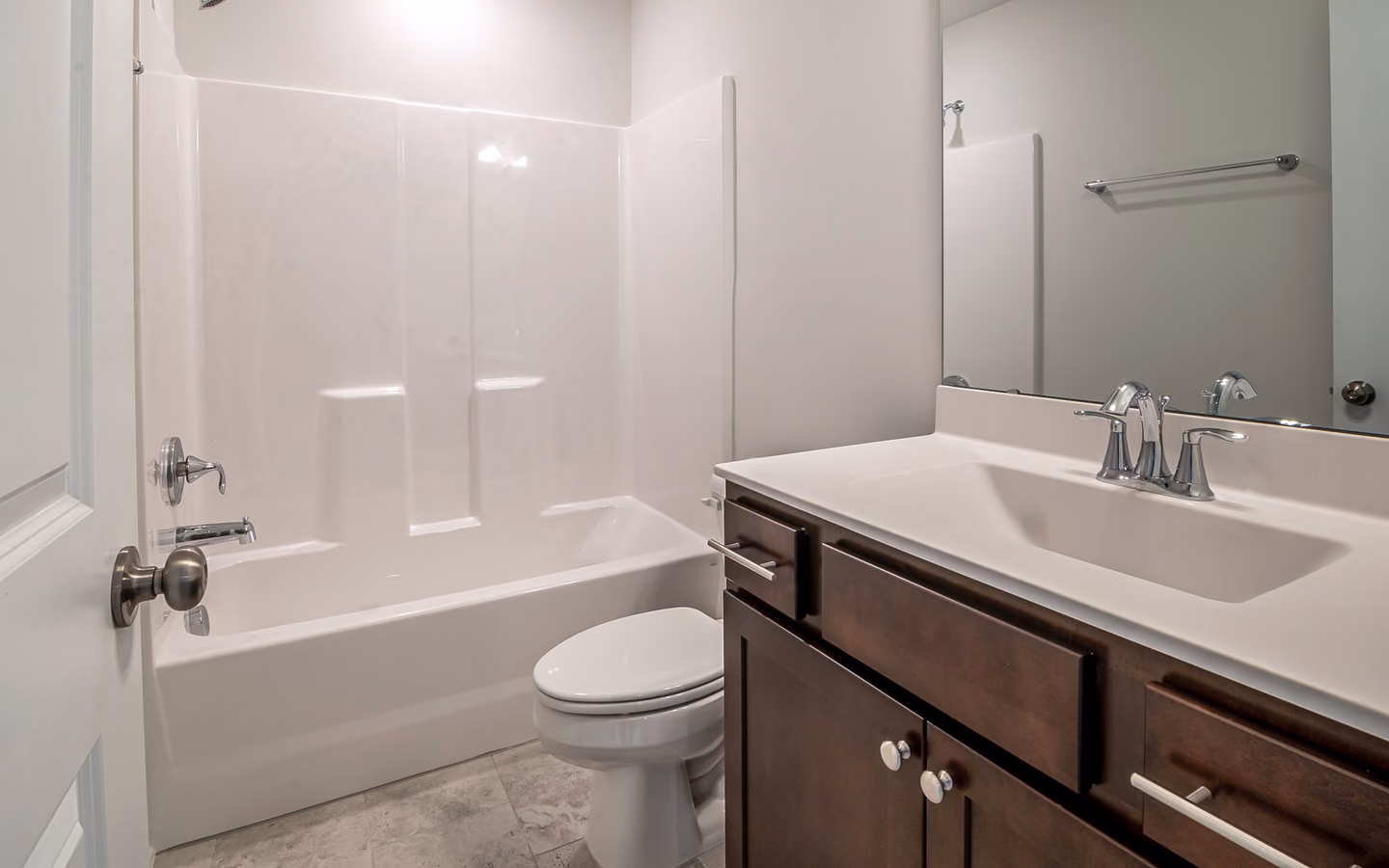 Clean bathroom layout with a bathtub, compact vanity, toilet, and simple white finishes