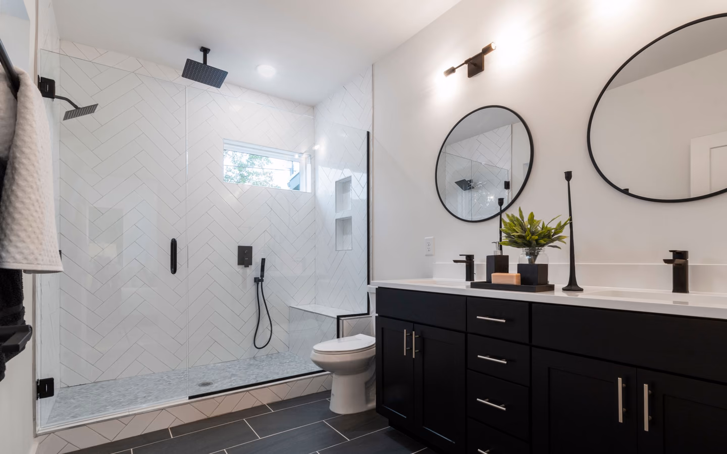 Contemporary bathroom with a black vanity, twin round mirrors, and a glass shower