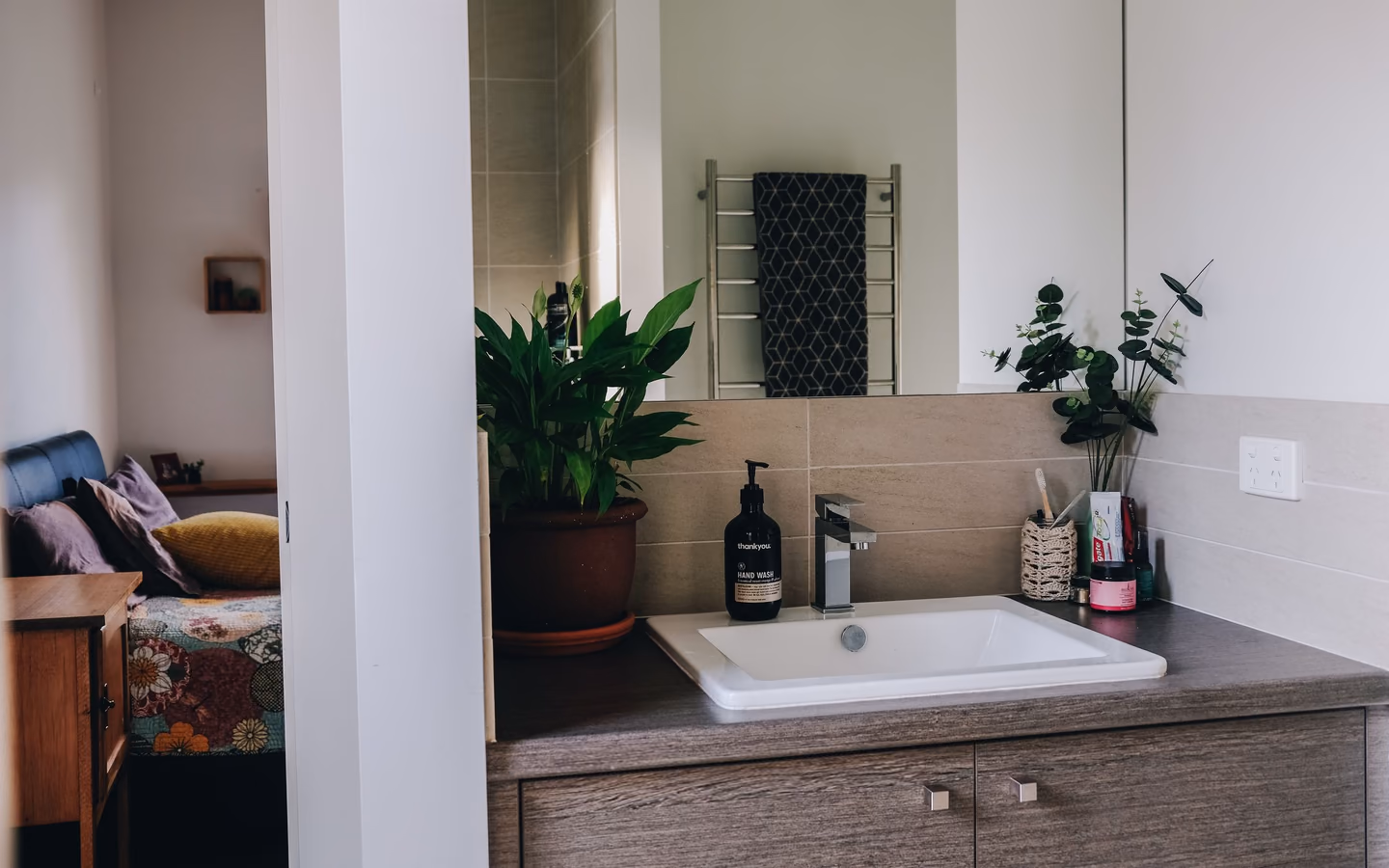 Organic modern bathroom with a wood vanity, natural greenery, and soft neutral finishes