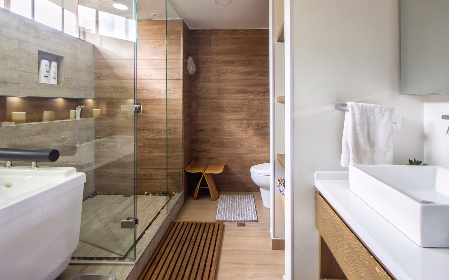 Contemporary bathroom with warm wood wall panels, a glass shower, and a freestanding tub
