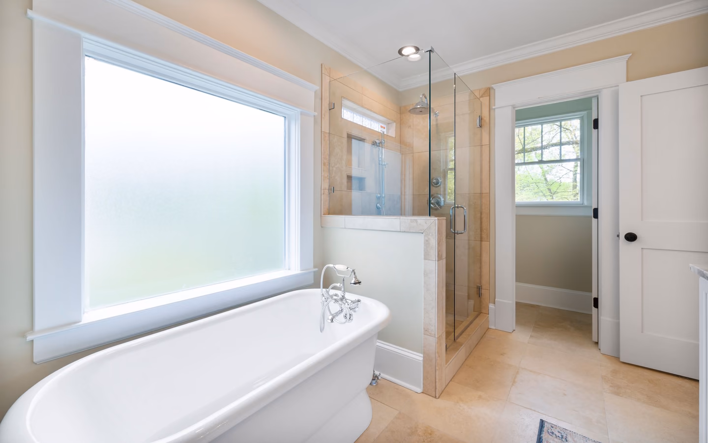 Bright spa-like bathroom with a freestanding tub, glass shower, and natural light