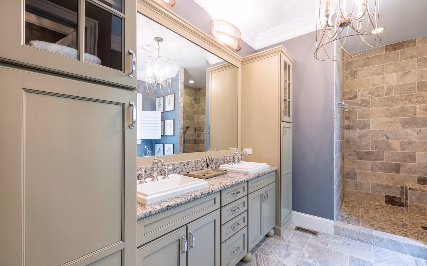 Updated traditional bathroom with tailored sage cabinetry, stone counters, and a glass shower