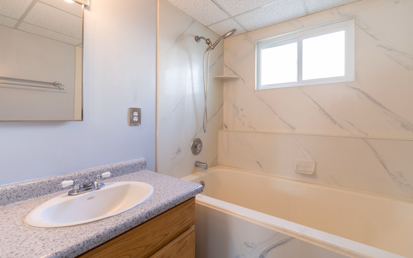 Bright practical bathroom with a vanity and glass-screened shower-tub