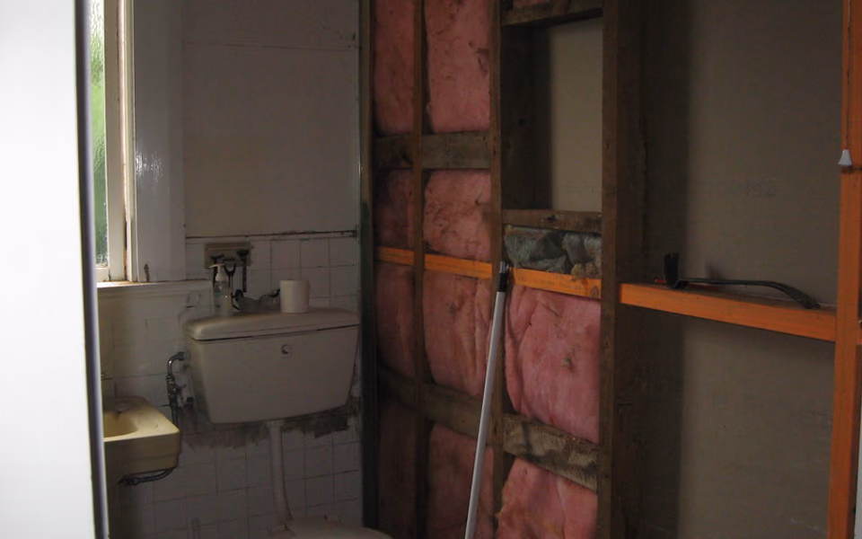 Open bathroom wall showing framing, insulation, and electrical routes
