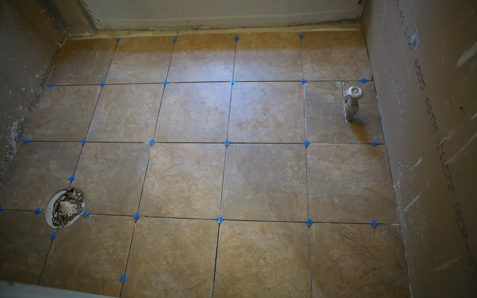 Bathroom floor tile laid around a shower drain and plumbing rough-in