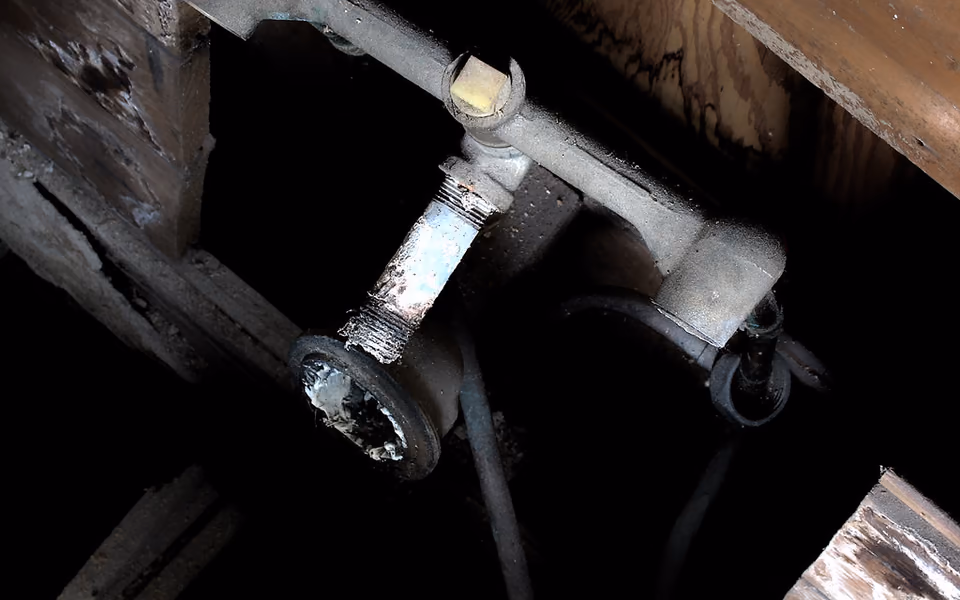 Old bathroom supply and drain pipes exposed below the floor