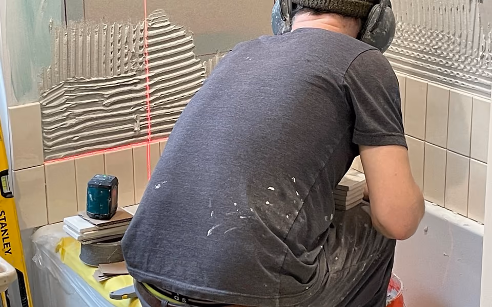 Tile installer working on a bathroom tub surround