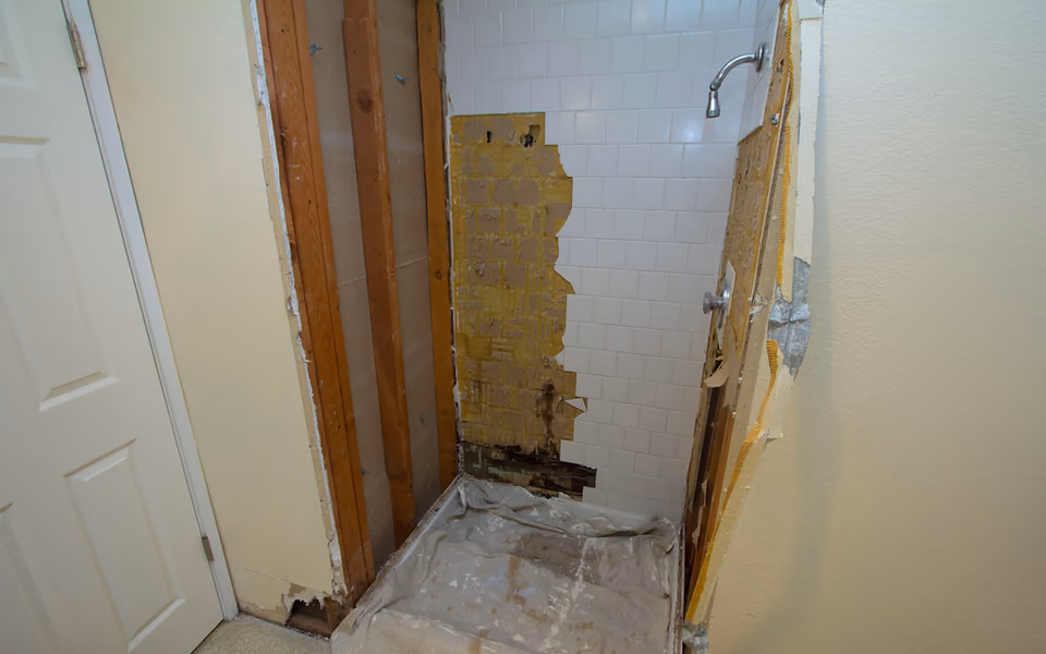 Shower wall opened to expose damaged backing and hidden moisture