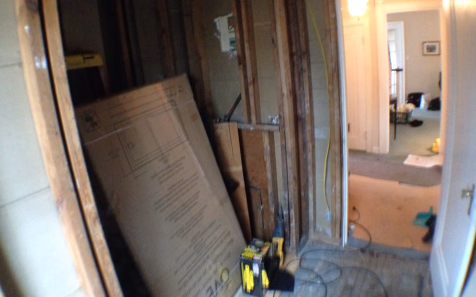 Bathroom remodel in progress with open wall framing and plumbing work