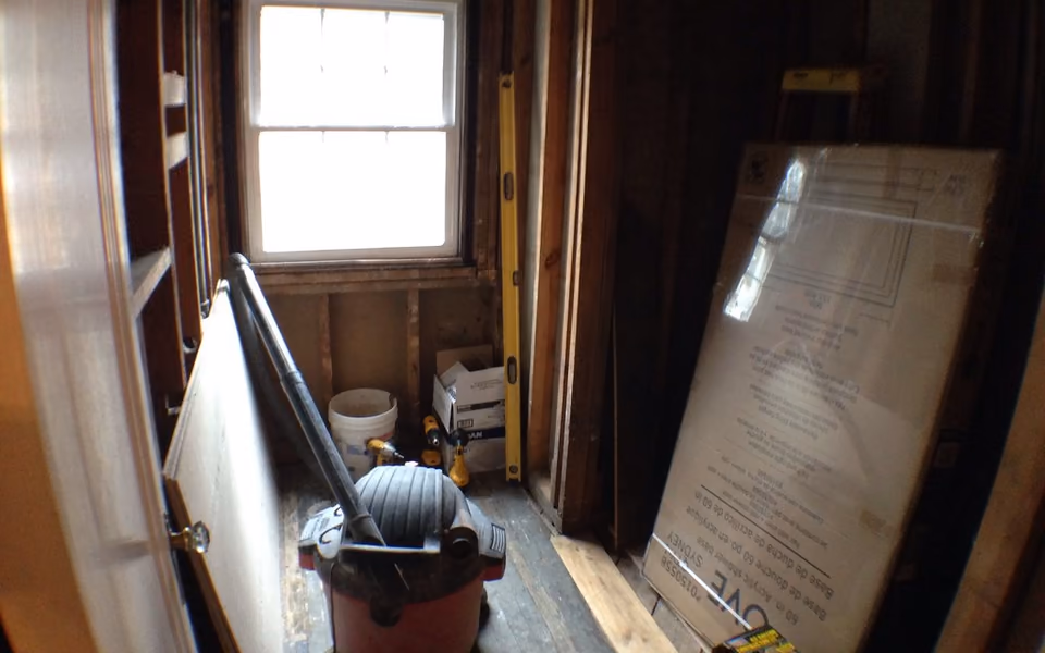 Bathroom demolition area with old wall cavities and protective building board