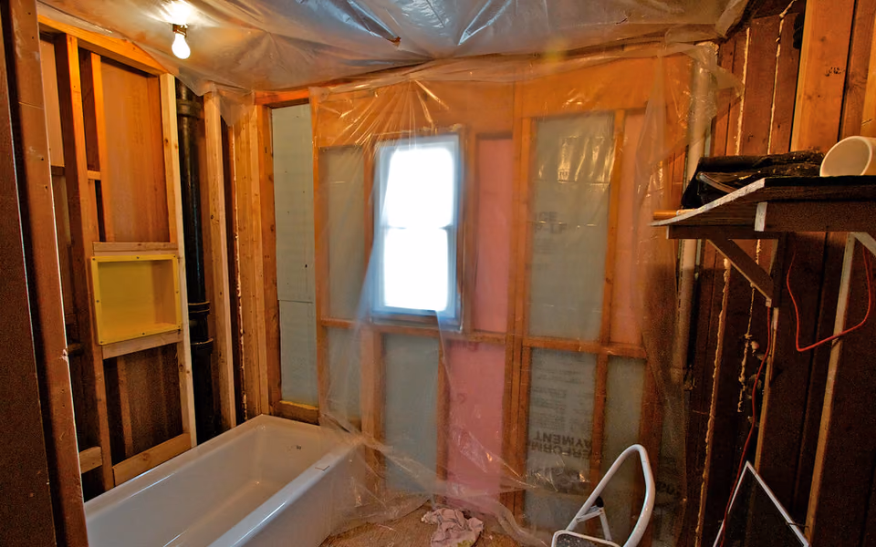 Bathroom demolition with wall cavities and insulation exposed