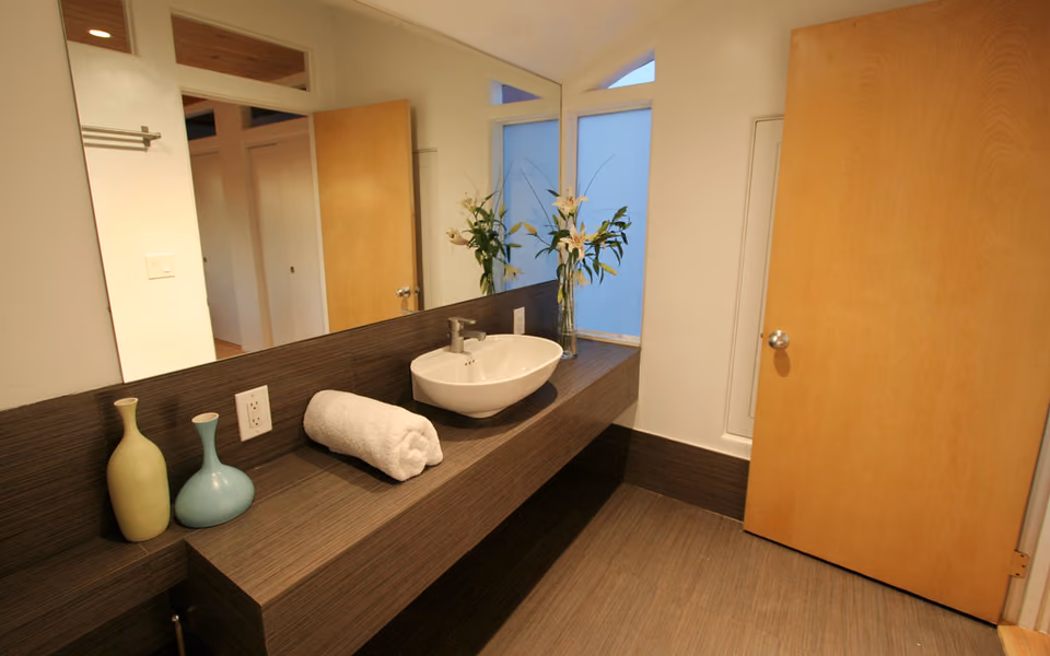 Modern bathroom vanity with a long counter, basin, mirror, and open doorway