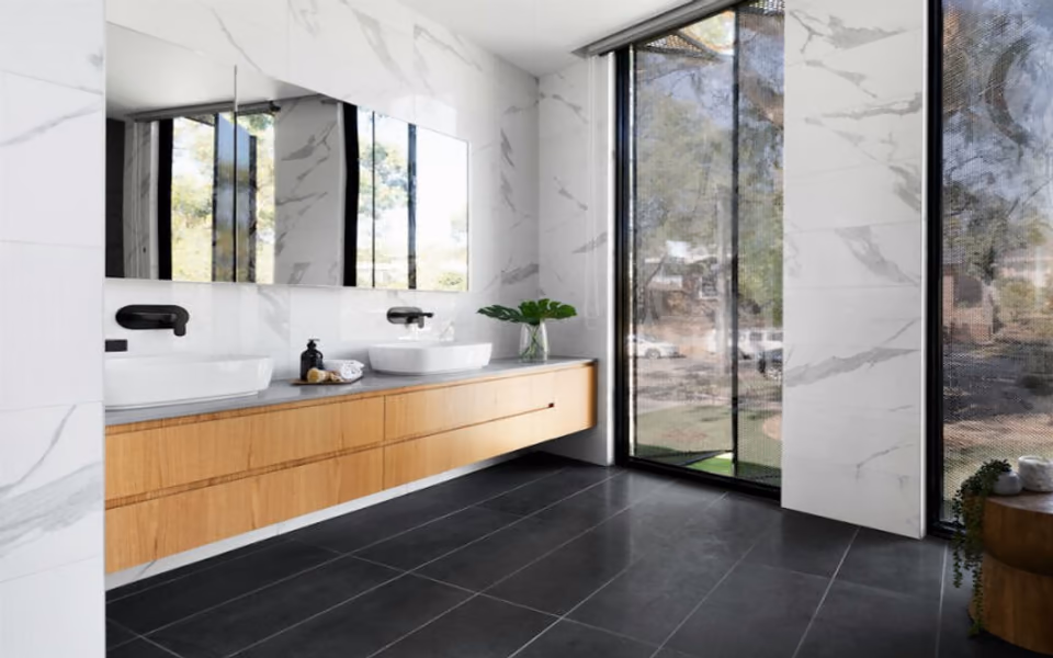Finished modern bathroom with marble walls, a wood vanity, and dark tile flooring