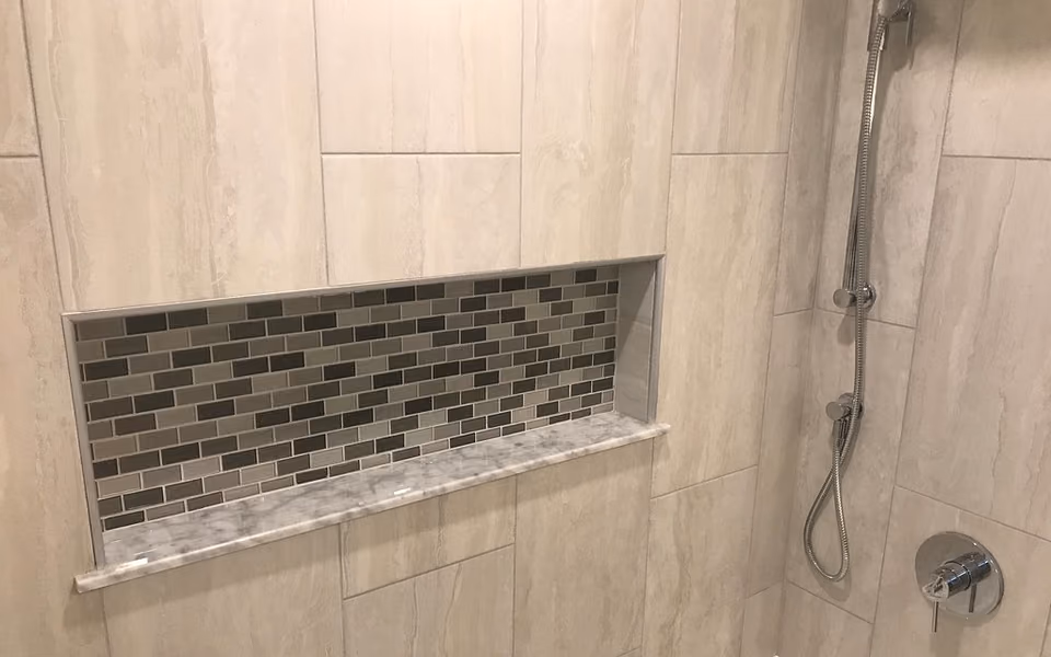 Recessed mosaic-lined niche in a finished tile shower