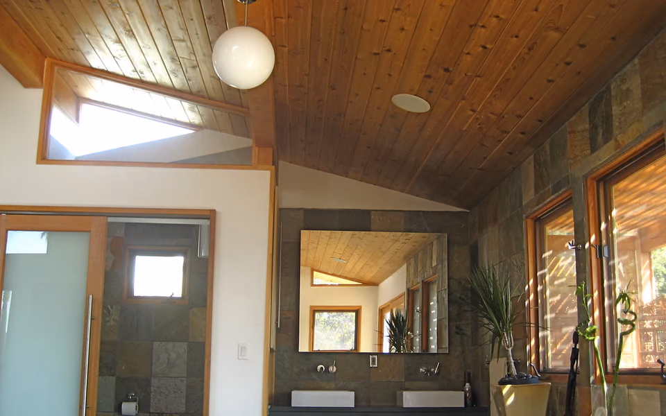 Bathroom with a tiled bathing area, high windows, and a wood ceiling